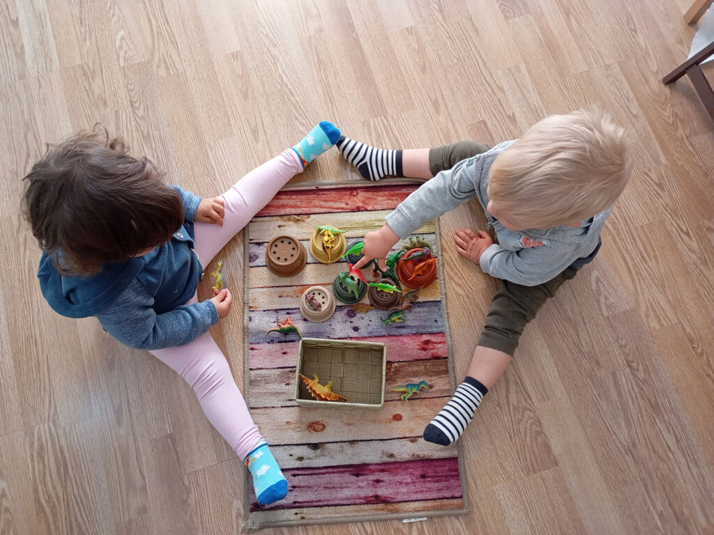 dos niños pequeños jugando juntos sentados en el suelo